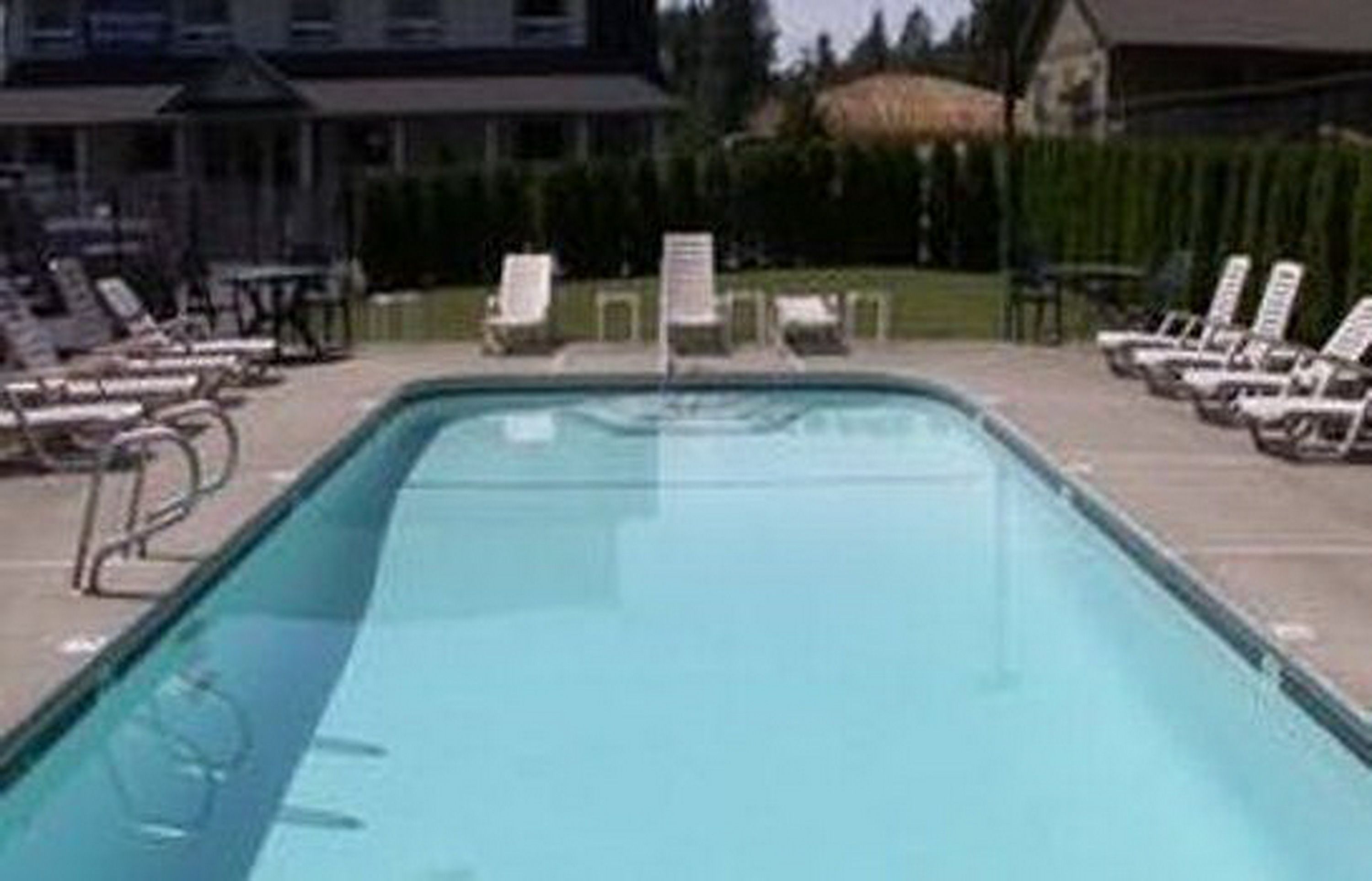 Una piscina con sillones de descanso y un cartel al fondo.