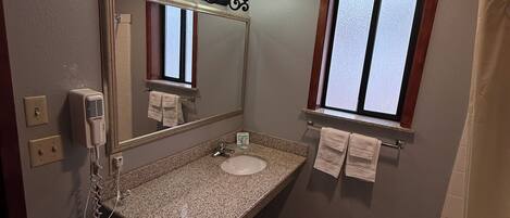 Baño con lavamanos de granito, espejo con luces arriba, ventana y cortina de ducha.