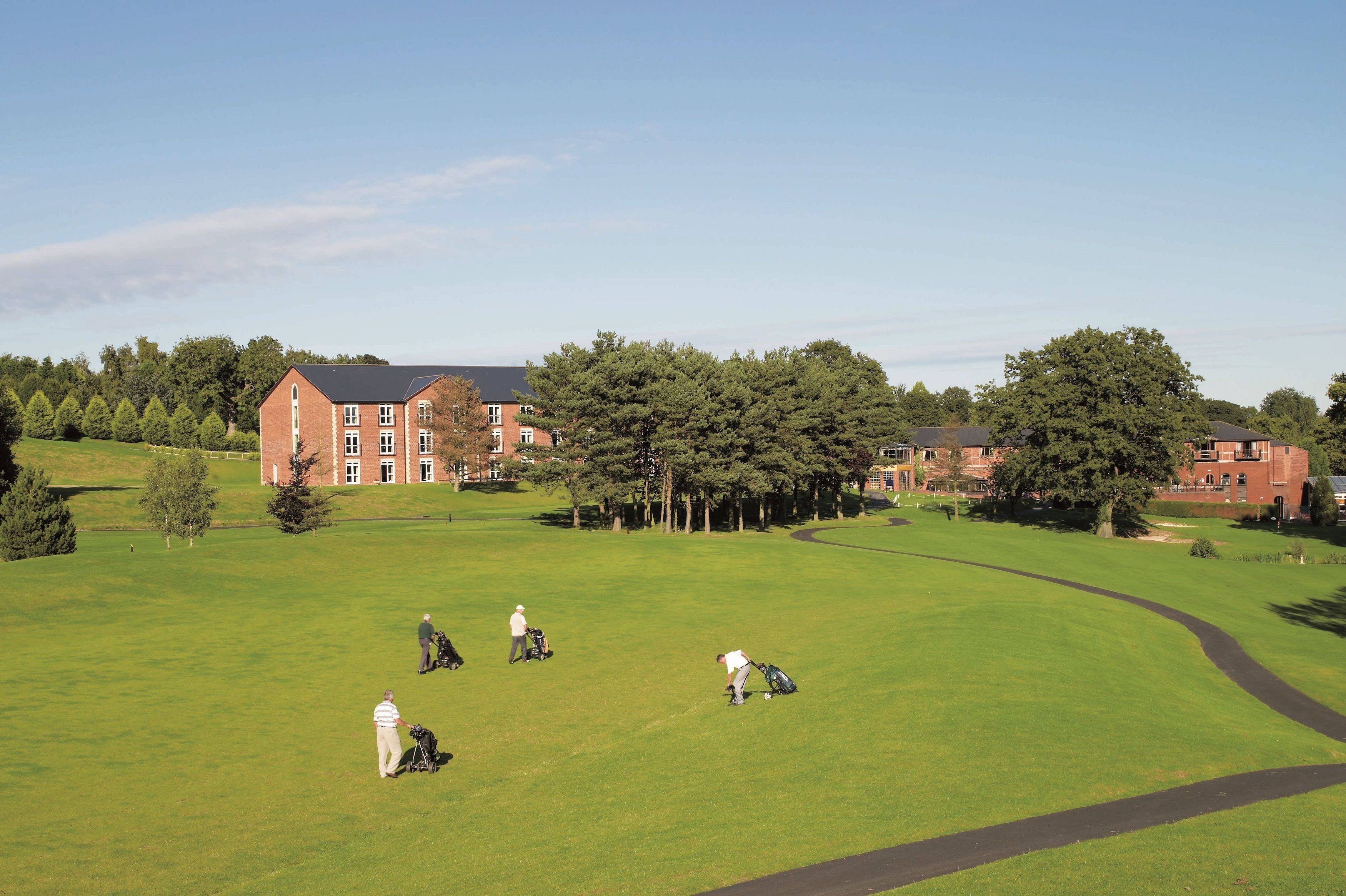 A golf course with a red brick building in the background.