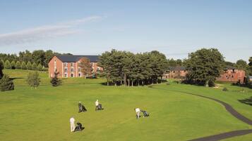 A golf course with a red brick building in the background.
