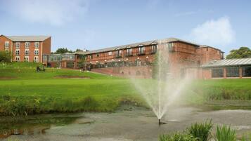 A building with a large water fountain in a grassy area.