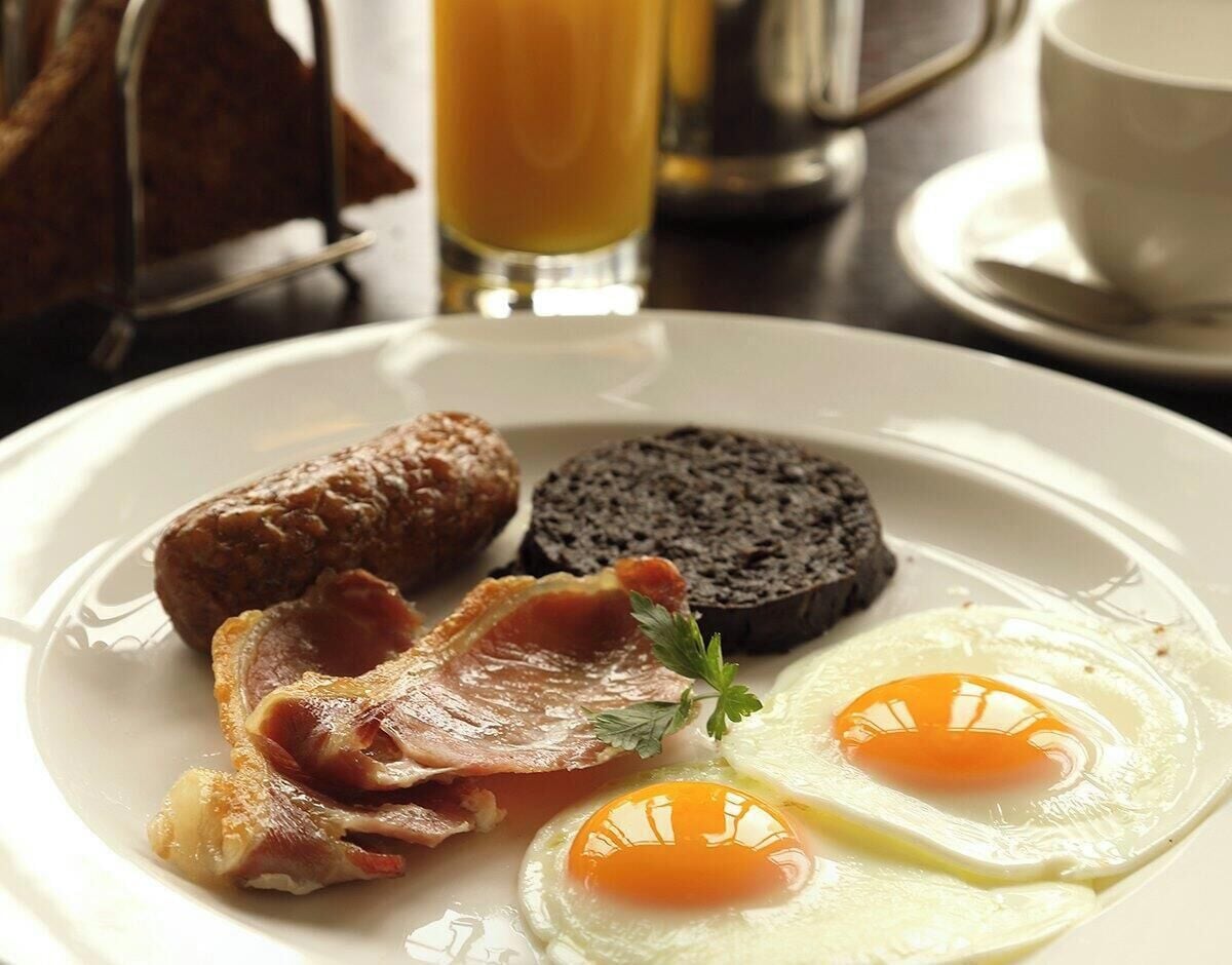 En morgenmadstallerken med æg, bacon, pølse og blodpølse.