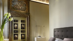 A bedroom with a large bed, a wooden floor, a decorative ceiling, and a door with artwork. - Locanda della Posta - Etruria Collection (Perugia)