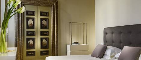 A bedroom with a large bed, a wooden floor, a decorative ceiling, and a door with artwork.