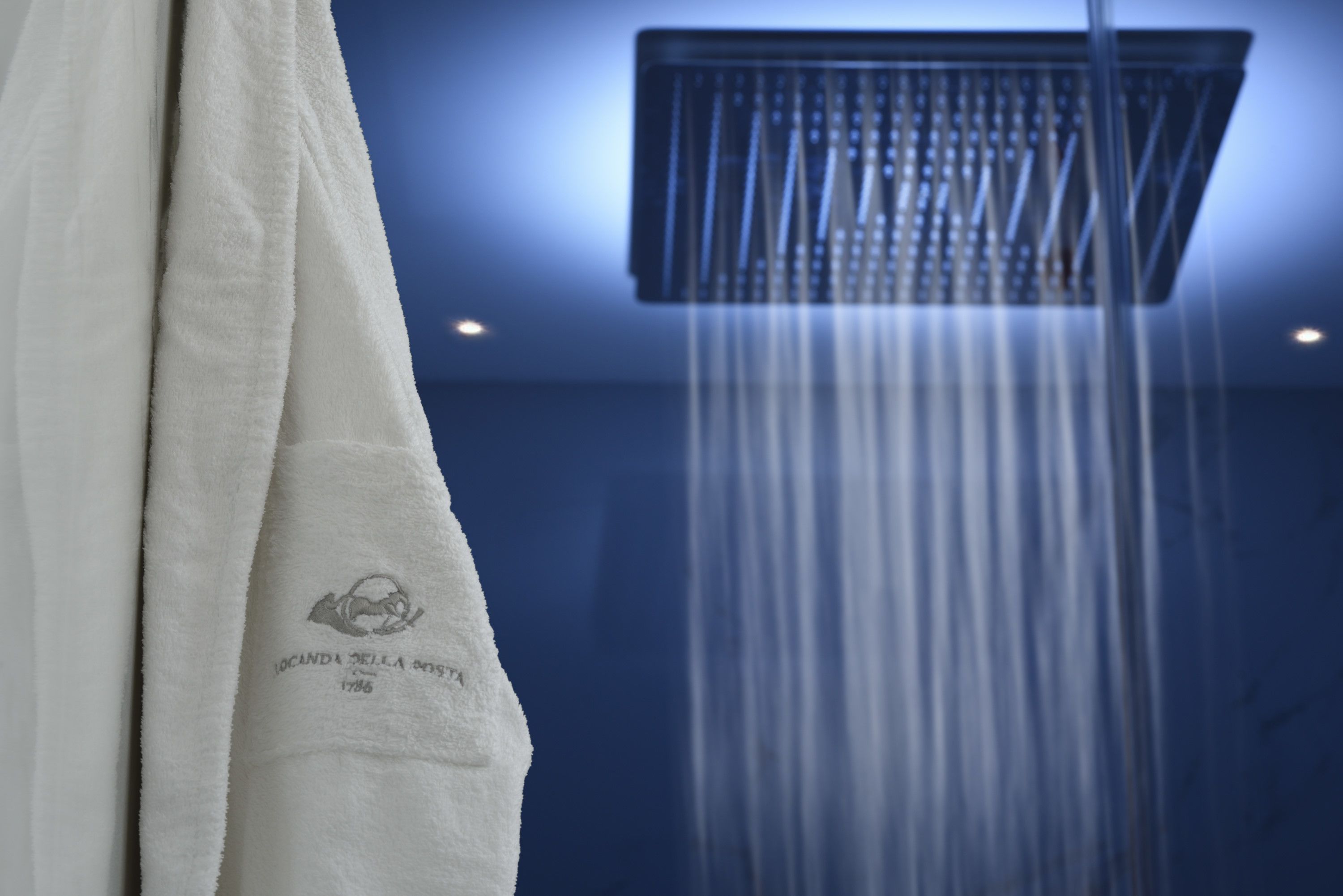 A towel hanging on a rack with a logo and text, and a showerhead with water flowing down.