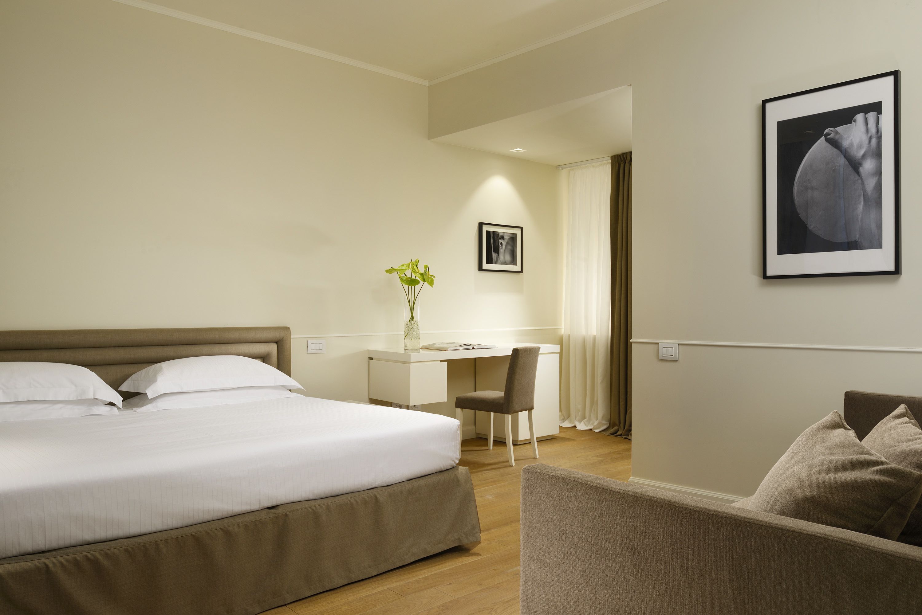 Una habitación de hotel con cama, escritorio, silla y sofá.