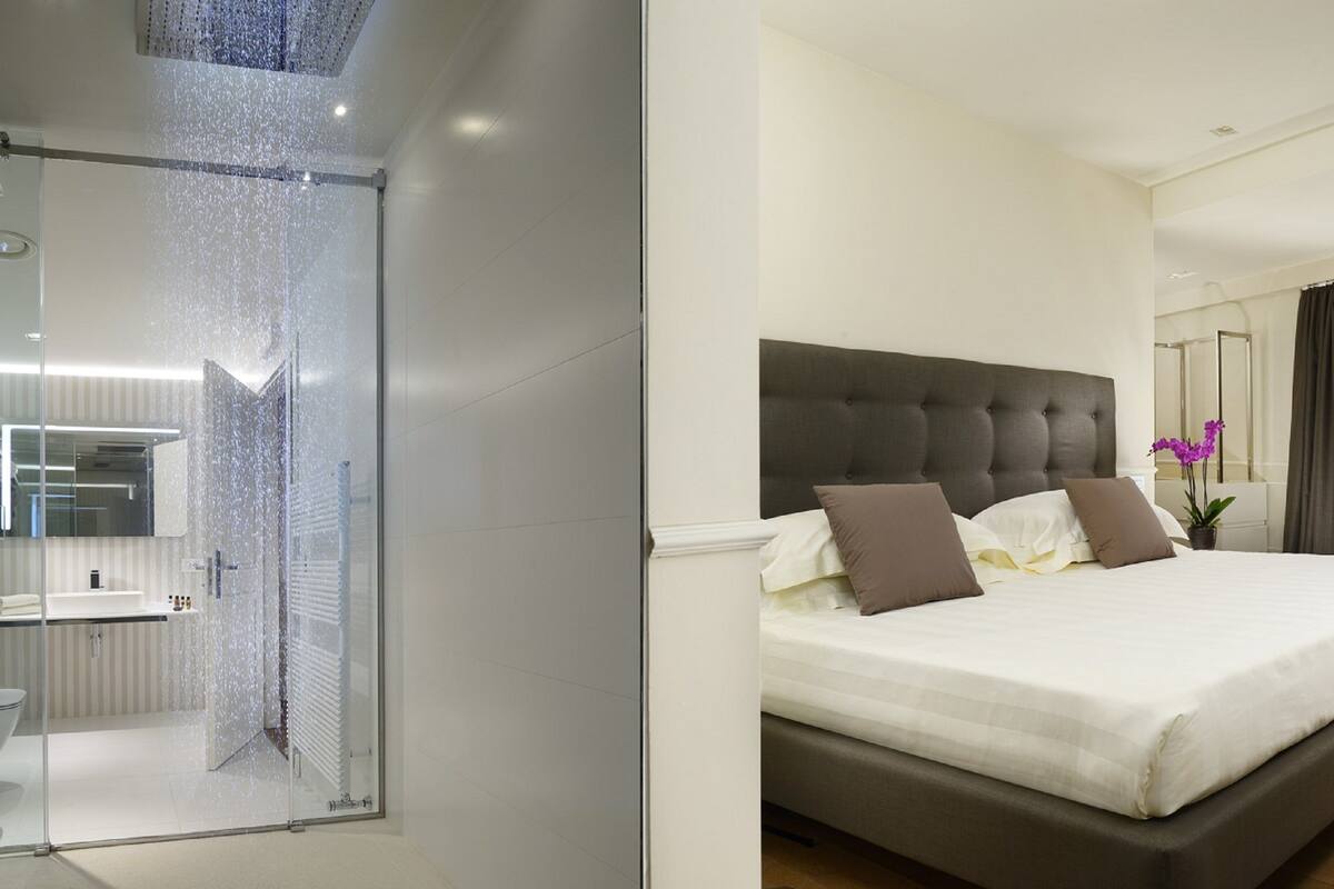 Une chambre d'hôtel moderne dotée d'un grand lit, d'une salle de bain avec une douche à parois de verre et d'un balcon offrant une vue agréable.