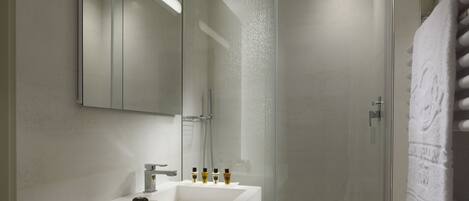 A modern bathroom with a glass-enclosed shower, a white sink, and a mirror above it.