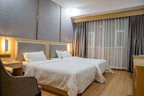 Una habitación de hotel con una cama grande, mesitas de noche, una silla y un escritorio.