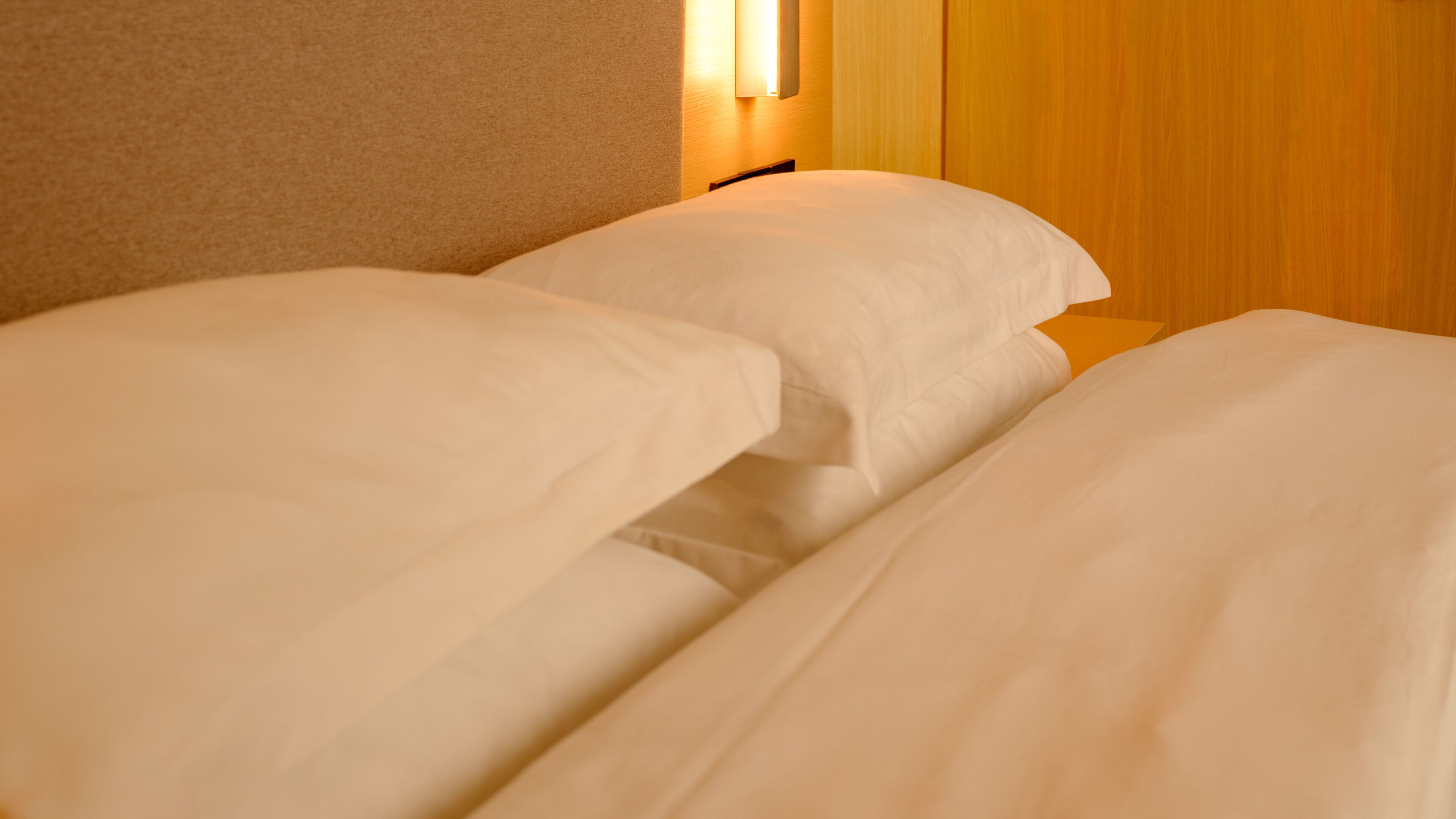 Una cama bien hecha con sábanas blancas en una habitación de hotel.