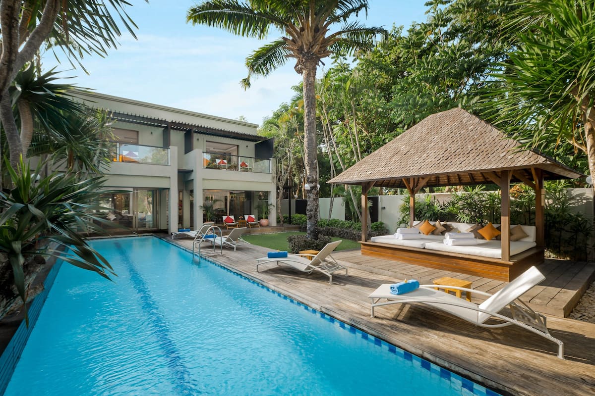 A pool area with lounge chairs, a wooden deck, and a gazebo.