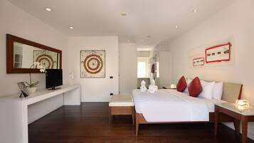 A modern hotel room with a large bed, a TV, a bench, and artwork on the walls.