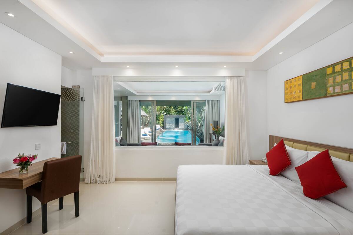 A modern hotel room with a bed, a desk, and a TV.