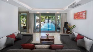 Una sala de estar moderna con un sofá grande, una mesa de centro y vistas a una piscina al aire libre.