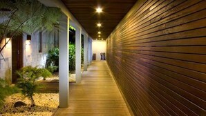 Un pasillo con listones de madera en un lado y un sendero con plantas y piedras en el otro.