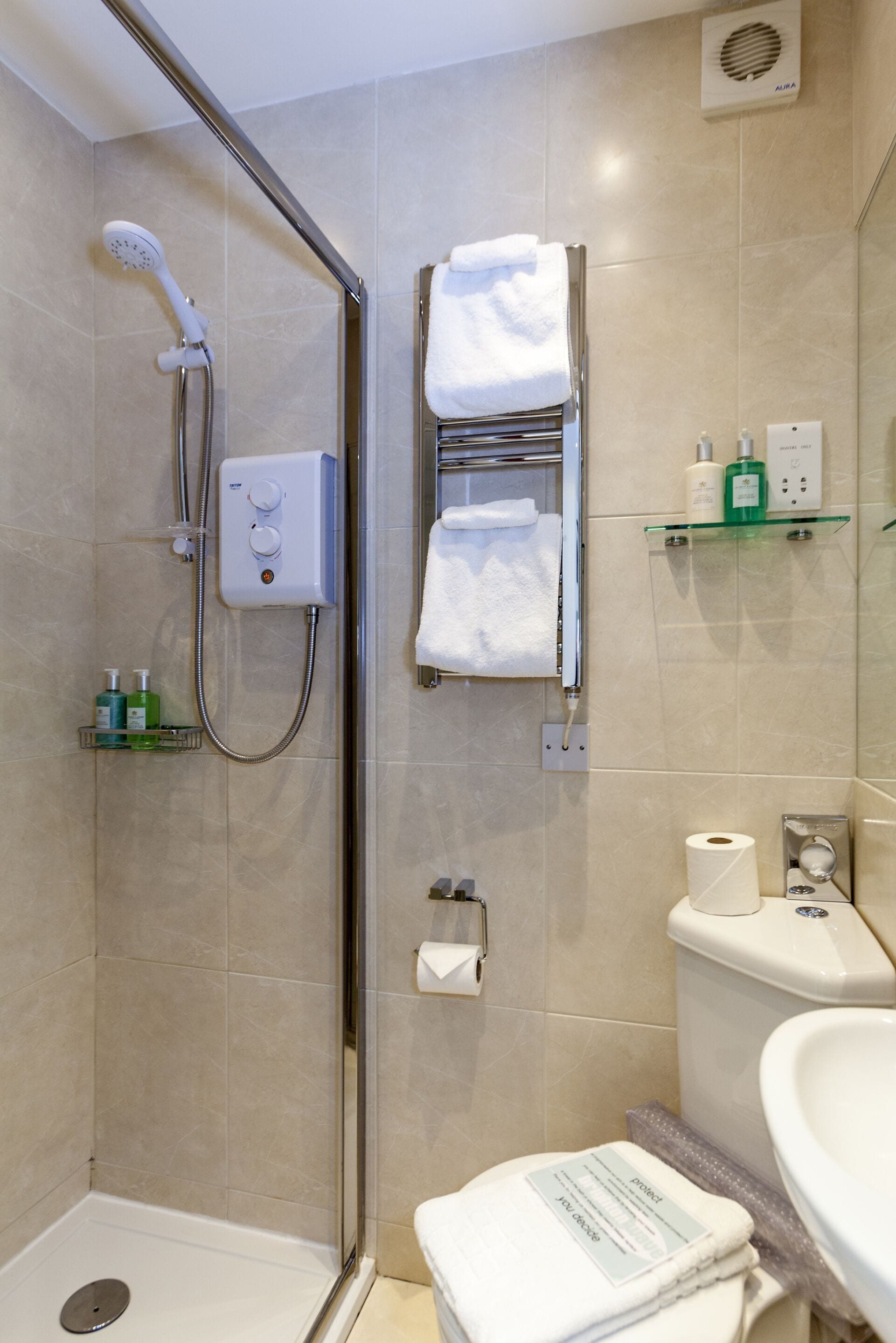 A modern bathroom with a glass-enclosed shower, a toilet, a sink, and a towel rack.