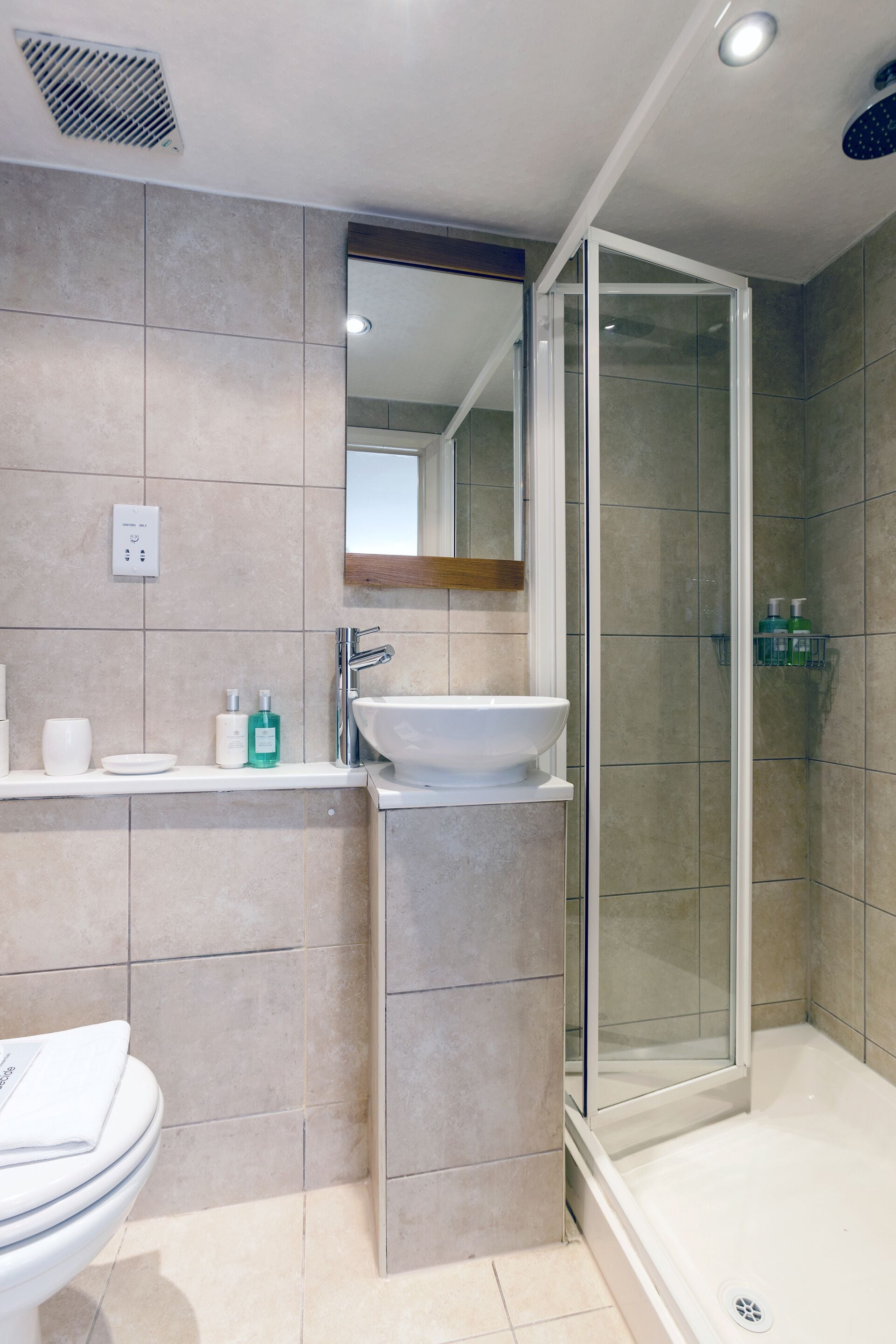 Un baño moderno con ducha cubierta de vidrio, un lavabo blanco y un inodoro.