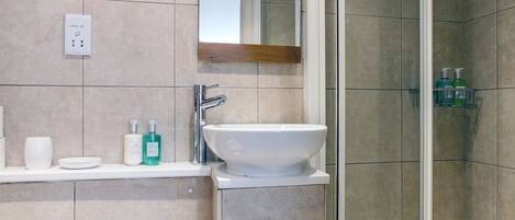 Un baño moderno con ducha cubierta de vidrio, un lavabo blanco y un inodoro.