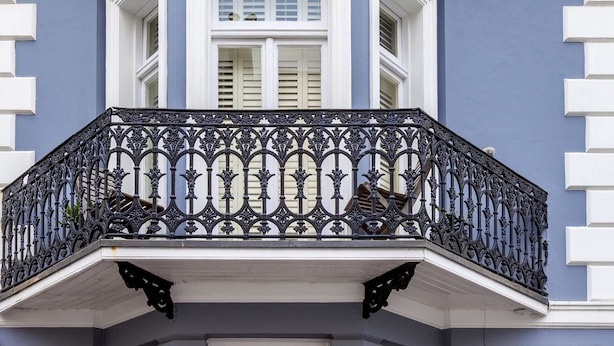 A building with a blue facade, white trim, and a black wrought iron balcony. - Brightonwave (Brighton)