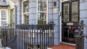 A building with a black door, a window with a sign, and a black iron fence. - Brightonwave (Brighton)