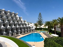 Una piscina al aire libre, sombrillas, sillones reclinables de piscina