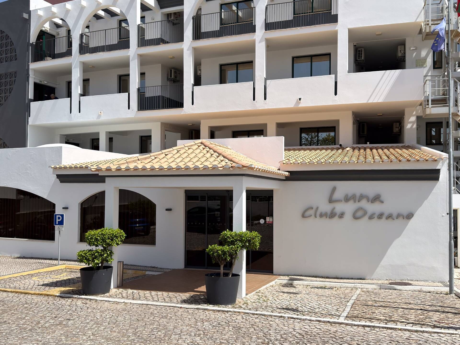 A multi-story building with balconies, a covered entrance, and a sign reading 'Luna Club Oceano'.
