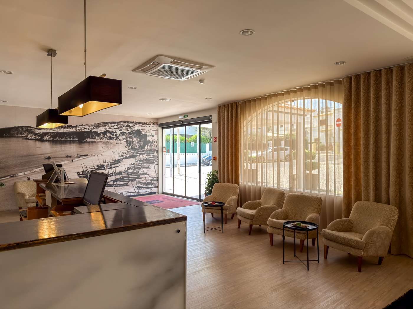 A hotel lobby with a reception desk, seating area, and a mural of a coastal scene.