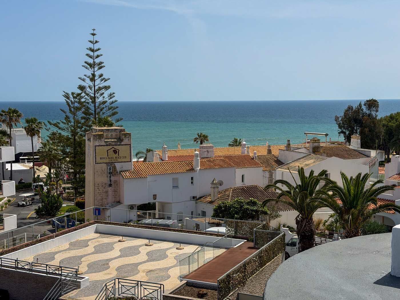 Un edificio costero con techo de tejas, una torre del reloj y vista al mar.