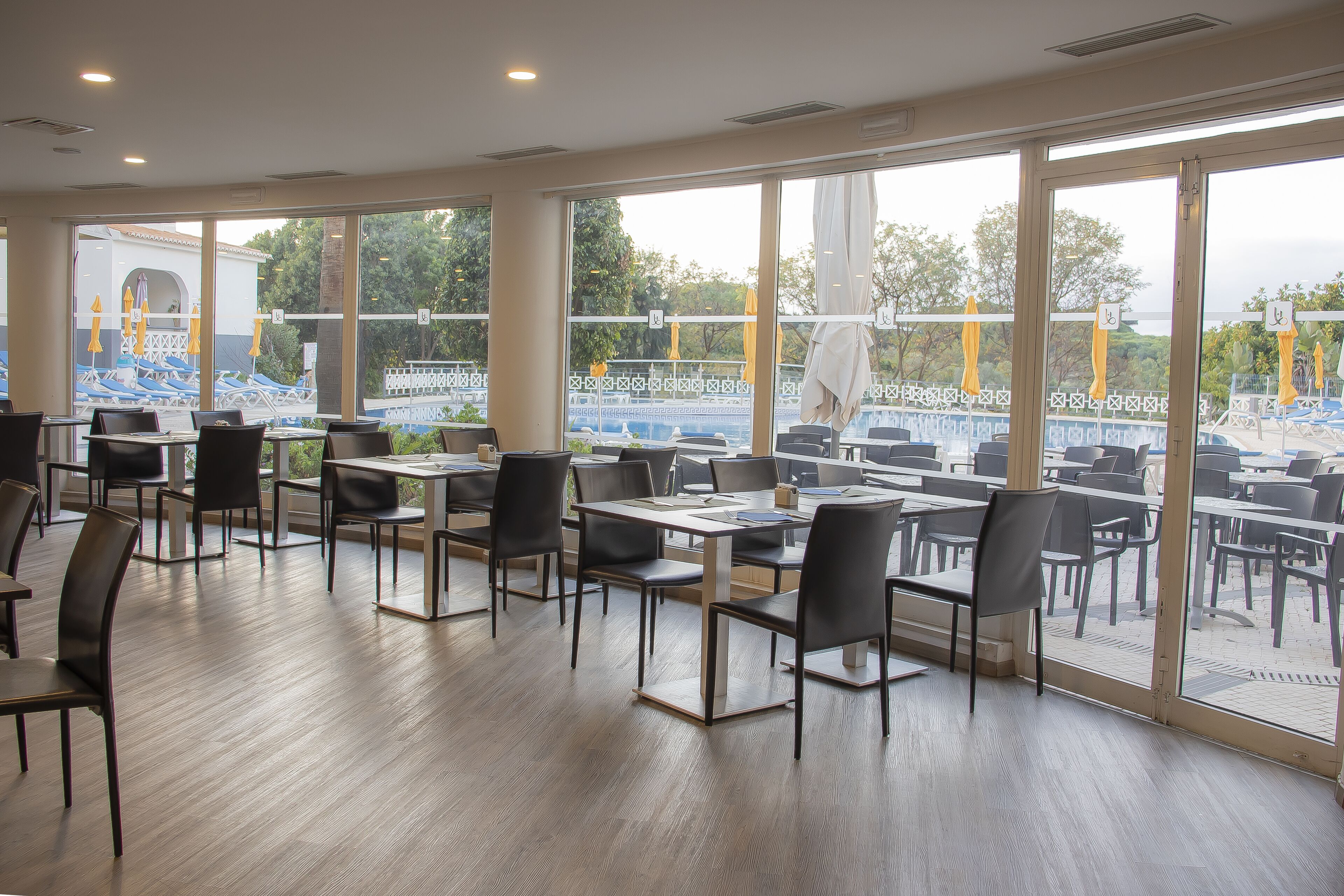 A spacious indoor dining area with large windows offering a view of an outdoor pool area.