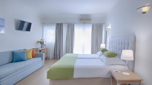 Een hotelkamer met een bed, een slaapbank, een nachtkastje met een lamp, een televisie aan de muur en gordijnen.