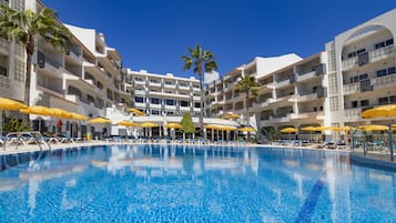 Una piscina techada, una piscina al aire libre, sombrillas