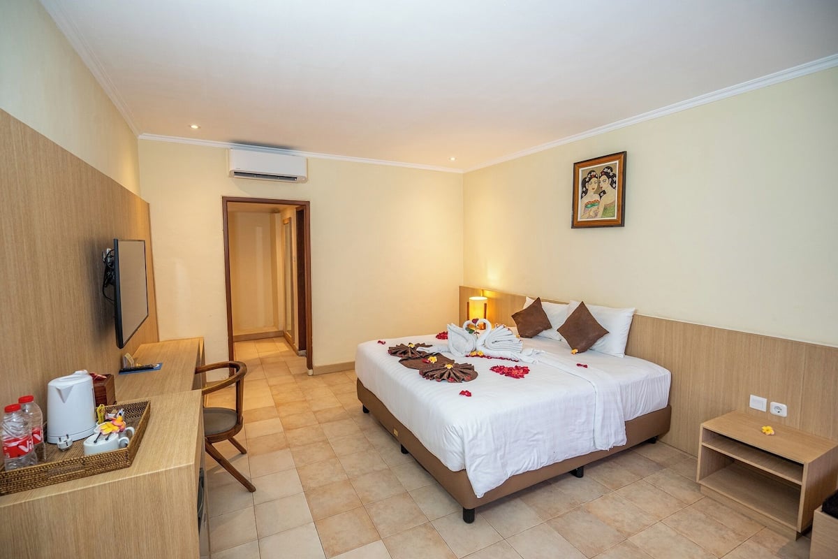 Une chambre d’hôtel comprenant un lit, une table de chevet, une chaise, un bureau et un téléviseur.