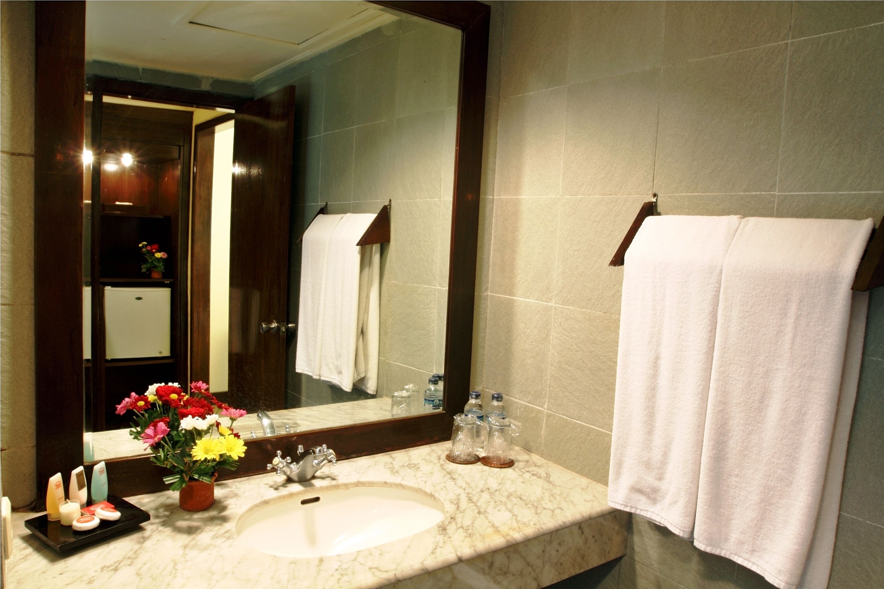 A bathroom with a marble sink, a large mirror, and a towel rack.