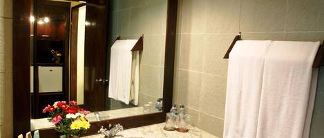A bathroom with a marble sink, a large mirror, and a towel rack.