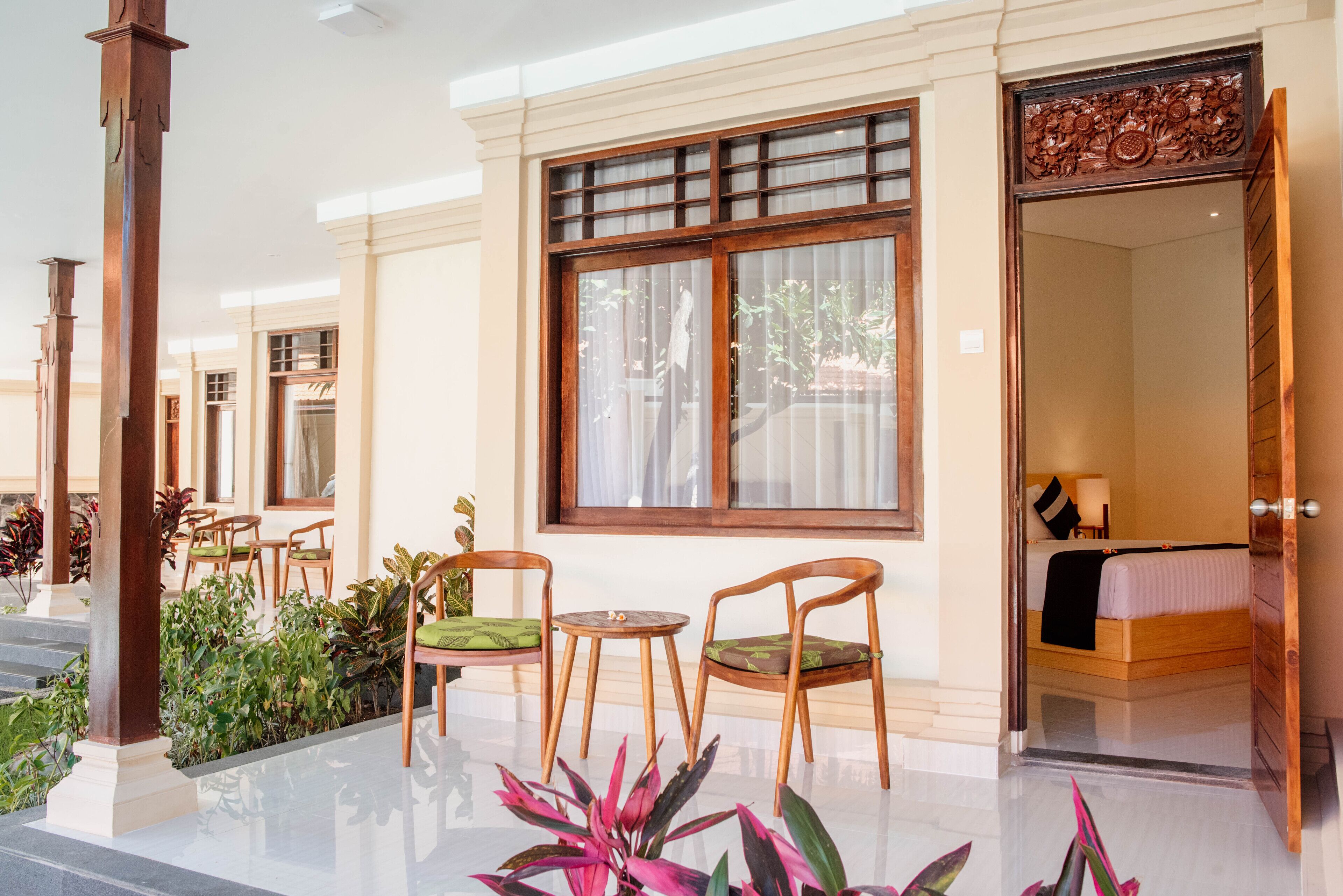 A hotel lobby with a seating area, a large window, and a door leading to a bedroom.