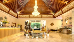 A spacious lobby with a high wooden ceiling, a central chandelier, and a reception desk. - New Sunari Lovina Beach Resort (Buleleng)