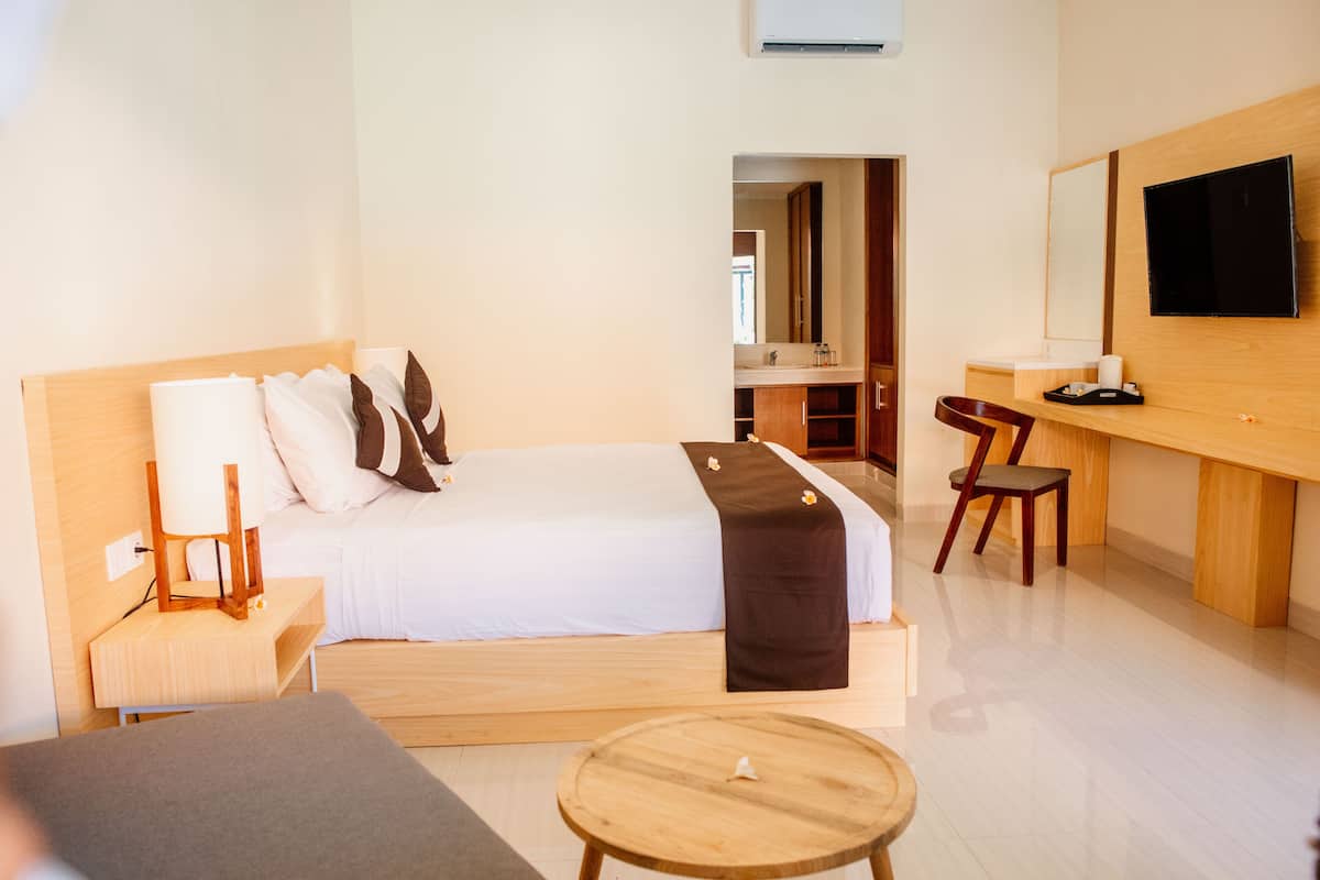 Une chambre d’hôtel moderne avec un grand lit, un bureau, une chaise et une petite table ronde.