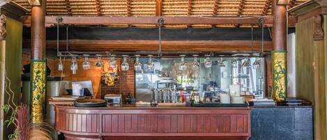 A bar area with wooden paneling, hanging light fixtures, and a counter with various items.