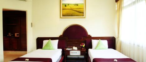 A hotel room with two beds, a nightstand, a painting of a field, and a wardrobe.
