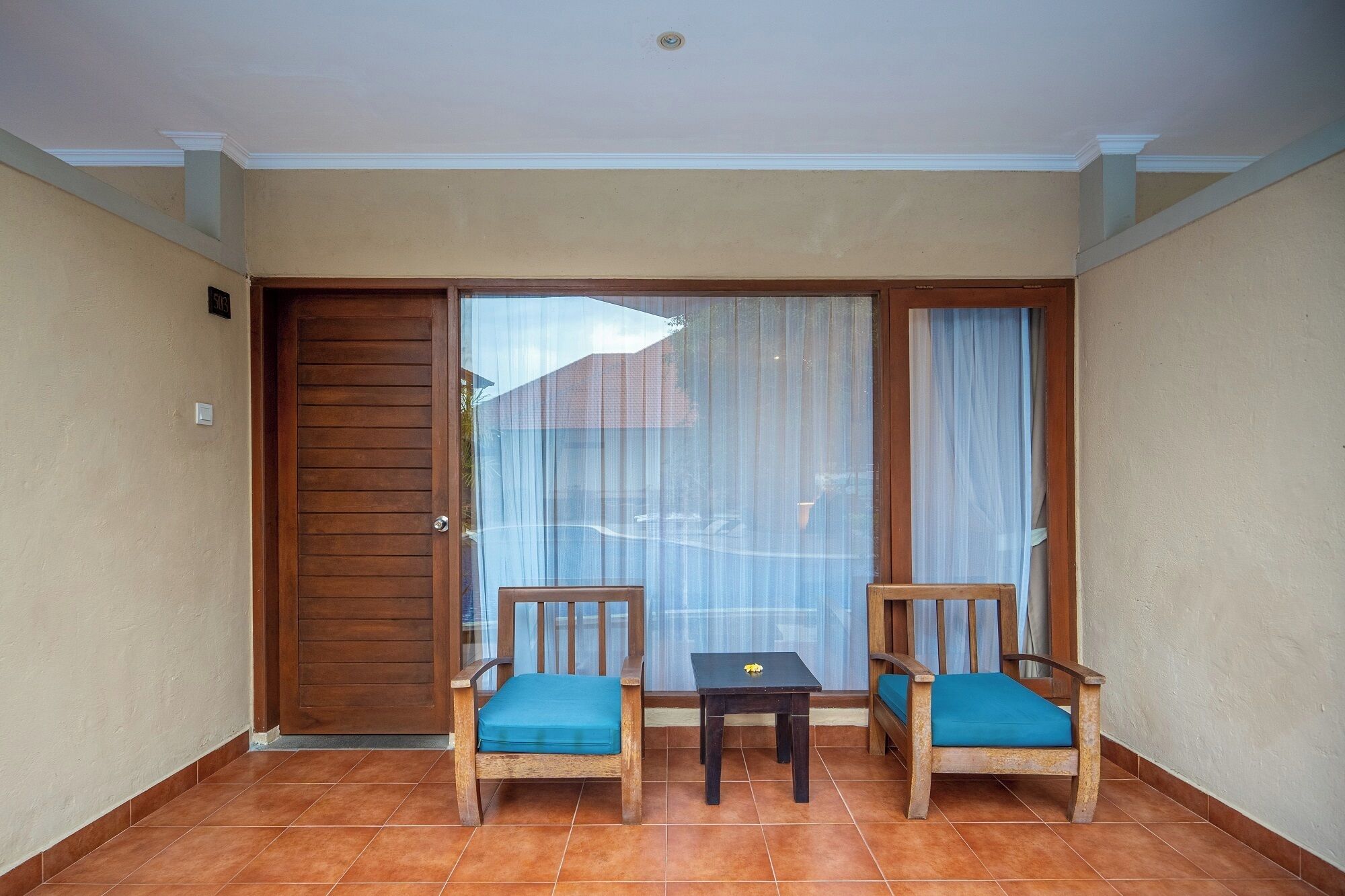 Ein Balkon mit zwei Holzstühlen, einem kleinen Tisch und einer Schiebeglastür.