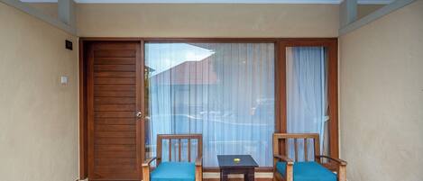 Ein Balkon mit zwei Holzstühlen, einem kleinen Tisch und einer Schiebeglastür.