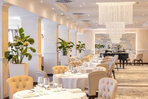 Un comedor formal con mesas redondas, manteles blancos y sillas cómodas.