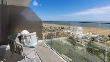 Un balcon avec vue sur la plage et un ensemble d’immeubles.