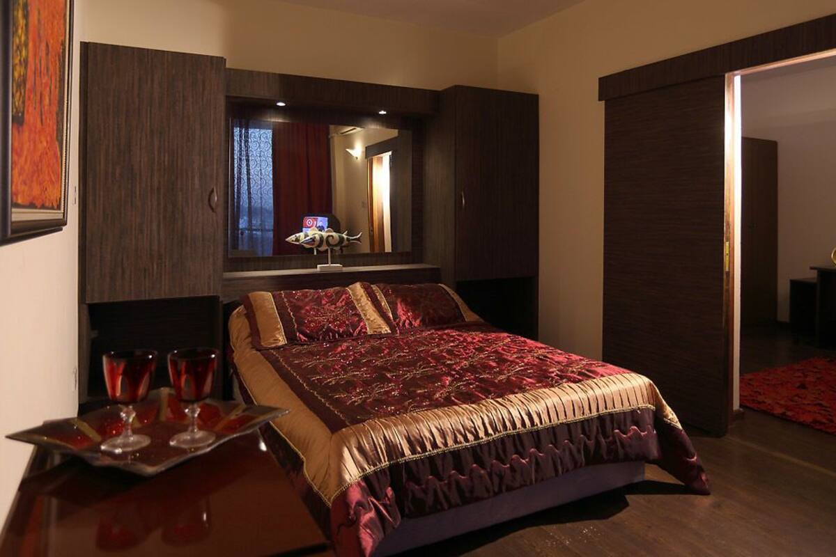 A hotel room with a large bed, a bedside table with glasses, and a mirror above the bed.