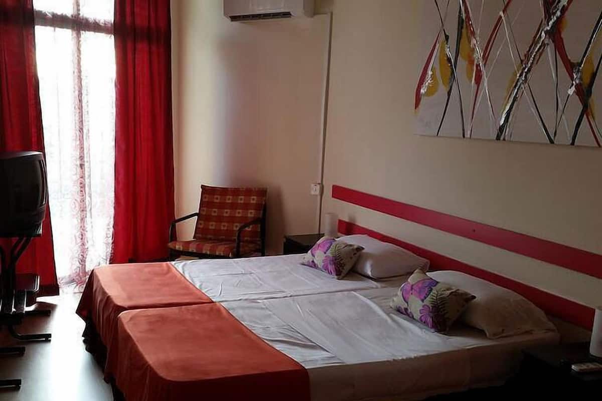 A hotel room with two beds, a chair, and a painting on the wall.