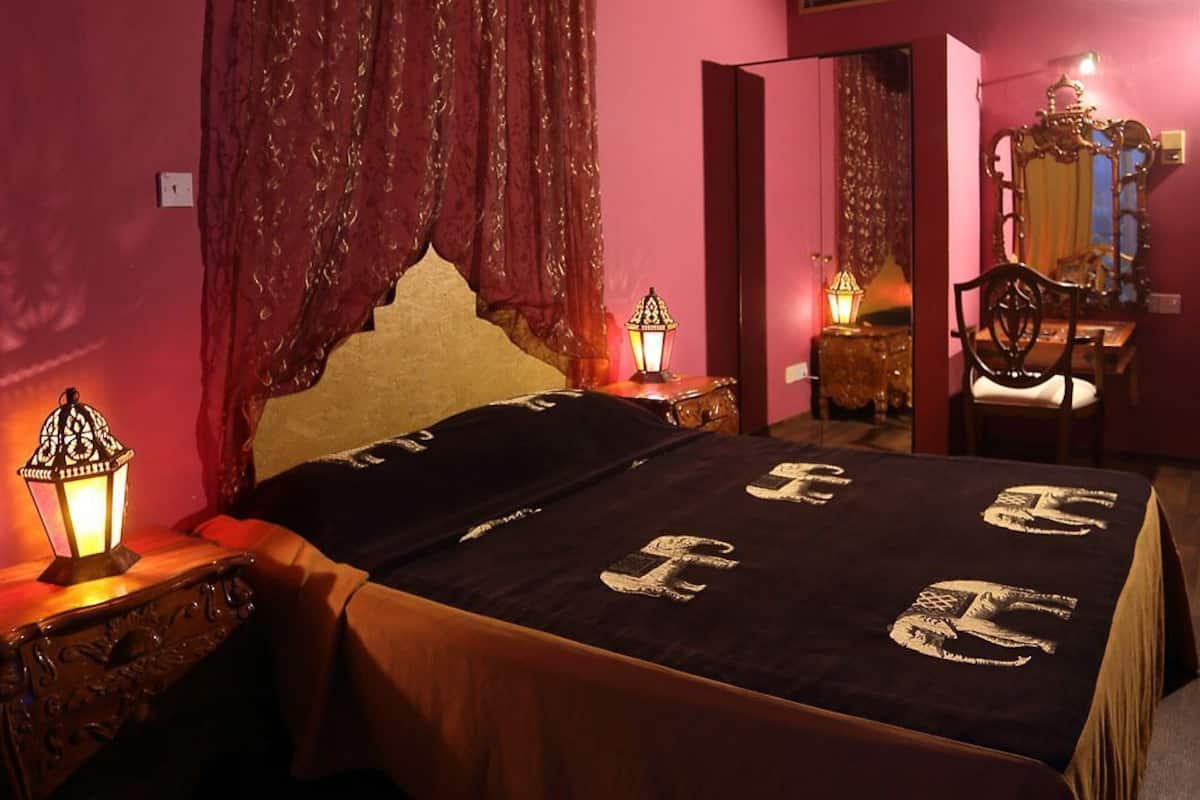 A bedroom with a canopy bed, a mirror, a star-shaped hanging light, and a patterned rug.