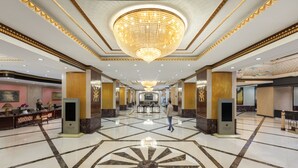 Eine großzügige Lobby mit einem großen Kronleuchter, Marmorboden und einer Rezeption.