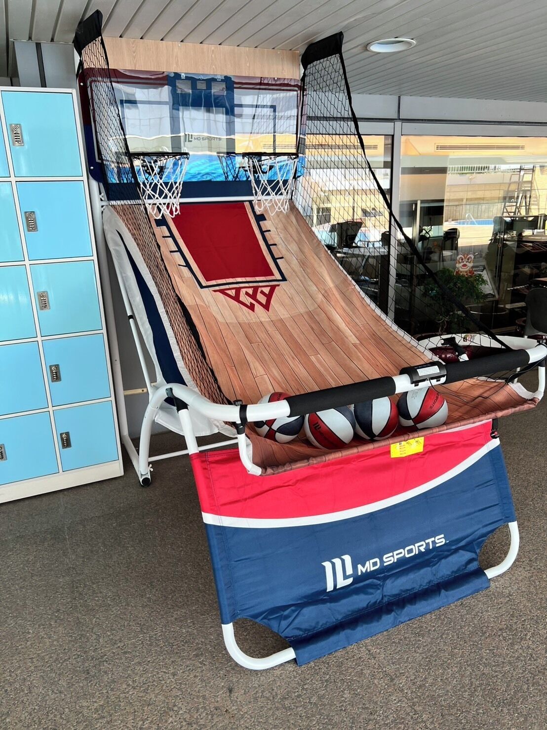 A sports training area with a netted floor, a red mat, and a blue and red sports bag labeled "MD SPORTS".