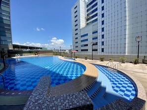 A swimming pool with checkered tiles, surrounded by a tiled deck and a building with a modern facade. - Evergreen Plaza Hotel Tainan (Tainan)