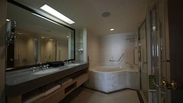 A modern bathroom with a large mirror, two sinks, a bathtub, and a glass shower enclosure.